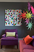 Bunte Papiersterne und Pixel-Bild an grauer Wand im Wohnzimmer