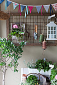 Wimpelkette vorm Gitter mit Gartenutensilien an der Hauswand