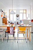 Dining table and various chairs in open-plan interior with retro ambience