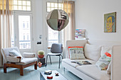 Helles Sofa, Stuhl und Sessel, Kugelleuchte mit buntem Stoffschirm im Altbau-Wohnzimmer mit Balkon