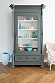Crockery in shades of blue in grey, glass-fronted cabinet