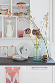 Artichoke flowers and branches of rose hips in vases decorating kitchen