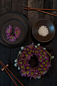 Floral wreath of purple flowers on a dark wooden table