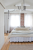 Layered blankets on a bed with a dust ruffle in the bright bedroom
