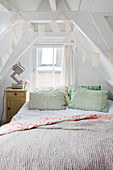 Bett mit Kissen in ausgebautem Dachgeschoss mit Holzkonstruktion