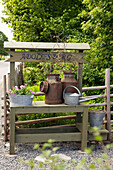 Old-fashioned wooden sales table, decorated with old zinc tub, milk jugs and watering cans