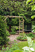 Archway in garden made of round wooden beams
