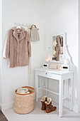 White console table and winter clothing in festively decorated hallway