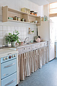 Vintage-style kitchen with curtains on base units