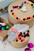 Cardboard boxes covered with pompoms and butterflies made of feathers