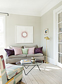 A feminine living room in pastel colours with wooden floorboards