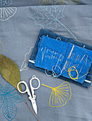 Embroidered cloth with autumn leaves, scissors and a sewing needle case