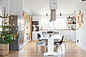 Kitchen in white with kitchen island and dining table that is decorated for Christmas