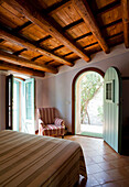 Mediterranean bedroom with terracotta tiled floor and door to garden