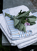 A bunch of sage leaves and geraniums on towels with striped trim