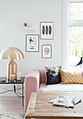 Rosa Polstergarnitur, goldene Tischlampe und rustikaler Couchtisch im Wohnzimmer