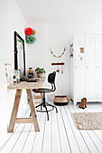 Wooden dressing table and black swivel chair on a white plank floor