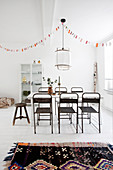 Old metal chairs at a table under a garland in a dining room with a white floor