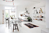 Lichtdurchflutetes Esszimmer mit weißem Boden und Vintage-Deko, Blick in die Küche