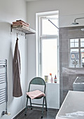Klappstuhl und Garderobe im Badezimmer mit Fenster
