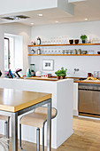 Bar stools at a high table in front of an open-plan kitchen