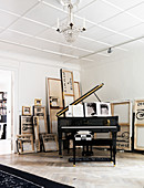 A grand piano in the corner on a room with painted canvases on the wall