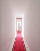 Long, white hallway with red runner in converted barn