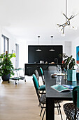 Dining table in large room with black open-plan kitchen at far end