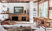 Sandstone fireplace, piece of rock in front, vintage leather armchair and animal fur rug in the living room
