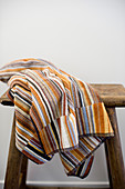 Towel striped in earthy shades on wooden stool