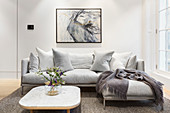 Grey modern sofa below abstract painting in living room