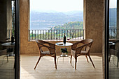 Korbsessel und filigraner Tisch auf mediterraner Terrasse mit Landschaftsblick