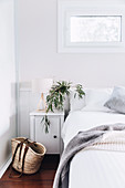 Basket in front of bedside cabinet in white bedroom