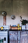Rustikale Küche mit Gasherd und altem Holzschrank vor grauer Wand