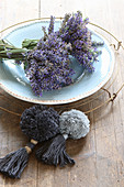 Posies of lavender on plate next to two pompoms with tassels