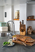 Aufgeschnittenes Brot und Kräuterbutter in rustikaler Küche