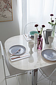 Place settings on white dining table with chairs