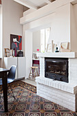 Fireplace in white brick chimney breast in dining room with colourful tiled floor