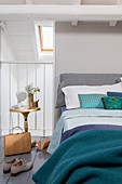 Double bed with blue and green textiles in attic room