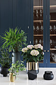 Hydrangea, thistles and twigs in black and golden vases