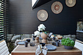 Set table in natural shades on terrace with exotic accessories