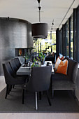 Dining table with upholstered chairs and bench in black, open-plan interior
