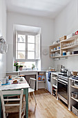 Helle Küche im Retrostil mit weißen Wänden und kleinem Esstisch