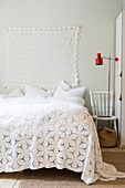 Lace cloth hung on wall above bed with romantic bedspread