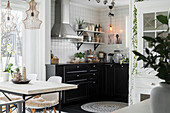 View across dining table into open-plan kitchen with black units