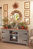 Gallery of pictures and mirror above grey, country-style sideboard