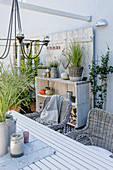 Table, wicker chairs and wooden shelves on terrace decorated for autumn