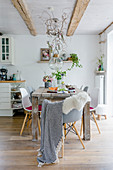 Esszimmer im skandinavischen Stil mit Holztisch, Klassikerstuhl und sommerlicher Pflanzendeko
