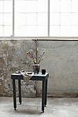 Table with vase and cake in front of concrete wall