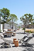 Deckchairs and wooden tables in gravel courtyard